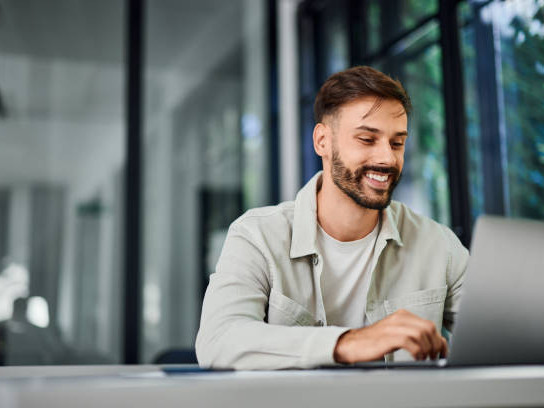 smiling man working over the laptop at the office
